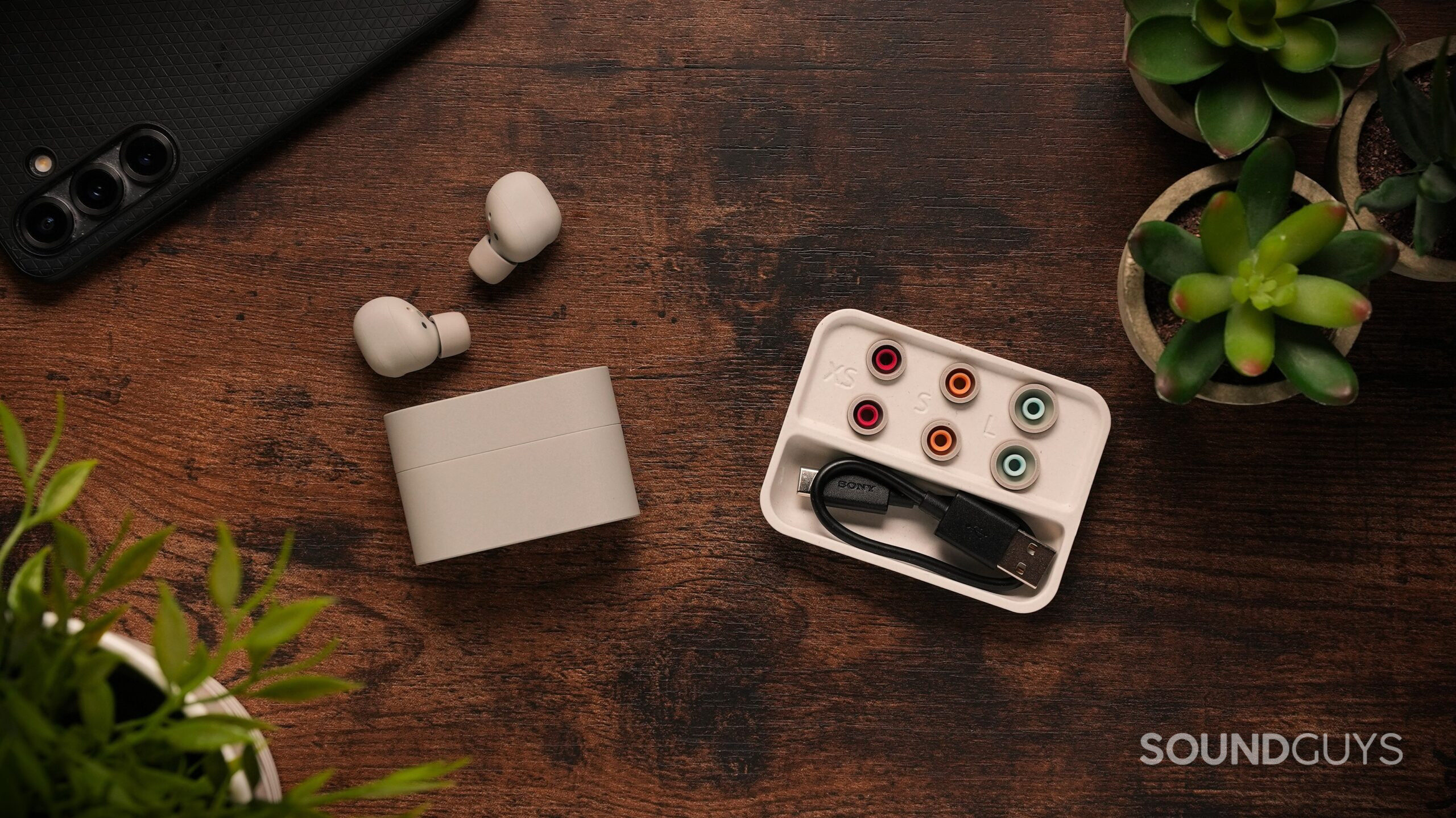 Wireless earbuds and charging cases arranged on a desk